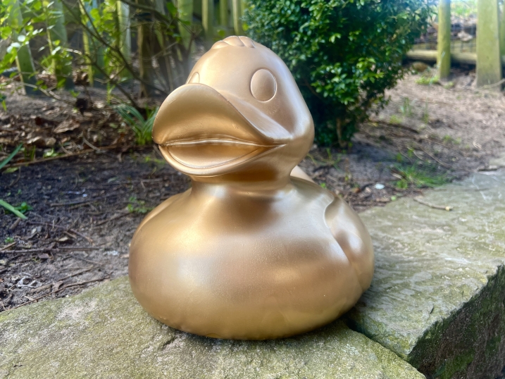 A golden giant rubber duck on a stone platform